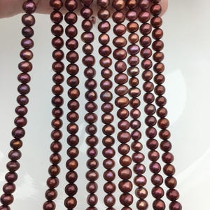 Peut inclure: Un brin de perles d'eau douce brunes. Les perles sont rondes et ont un léger éclat iridescent.