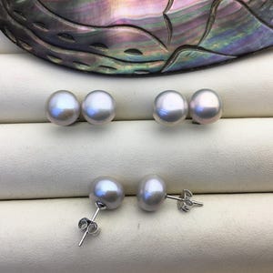 May include: A pair of pearl earrings with silver posts. The pearls are white and round.