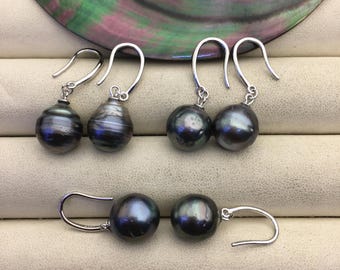 Pode incluir: Três pares de brincos pendentes com pérolas redondas, escuras e iridescentes suspensas por ganchos de metal prateado. As pérolas exibem tons profundos de carvão e preto com subtis matizes metálicos e um acabamento de superfície liso.