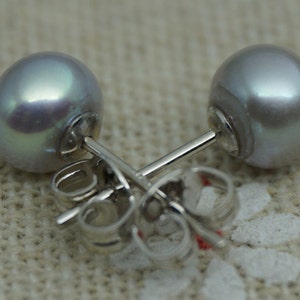 May include: A pair of silver stud earrings with a single, round, iridescent gray pearl on each earring.