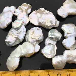 Pode incluir: Uma cole&ccedil;&atilde;o de 10 p&eacute;rolas barrocas brancas com tons iridescentes. As p&eacute;rolas s&atilde;o de forma irregular e variam em tamanho de 2,5 a 5 cm.