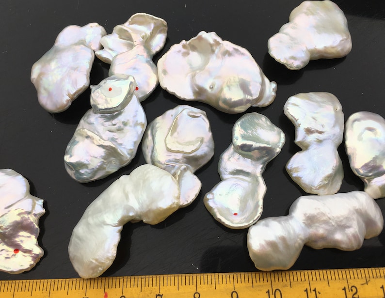 Pode incluir: Uma cole&ccedil;&atilde;o de 10 p&eacute;rolas barrocas brancas com tons iridescentes. As p&eacute;rolas s&atilde;o de forma irregular e variam em tamanho de 2,5 a 5 cm.