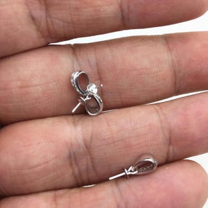 May include: Two silver-toned pearl clasps with a loop on one end and a pin on the other end.