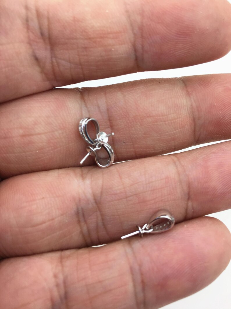 May include: Two silver-toned pearl clasps with a loop on one end and a pin on the other end.
