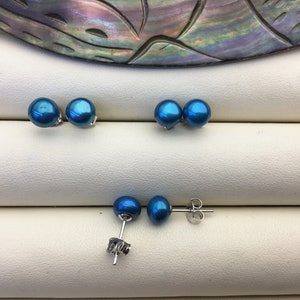May include: Three pairs of blue pearl earrings with silver posts. The pearls are round and have a smooth, glossy finish.