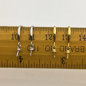 May include: Two pairs of earring findings, one pair is silver and the other is gold. The findings are shown on a ruler, measuring approximately 1 inch in length.