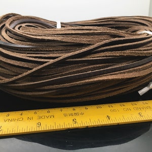 May include: A close-up of a brown leather cord, coiled and measured with a ruler. The ruler is yellow and reads "MADE IN CHINA" and "BRAND NO. 100".