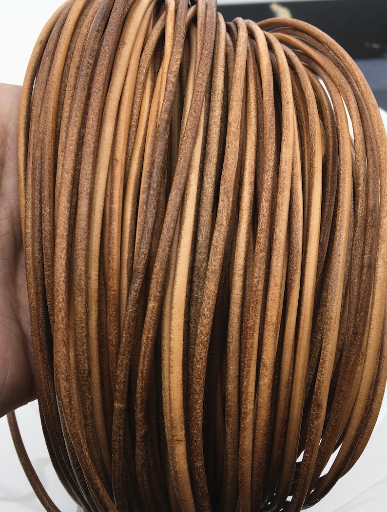 May include: A close-up of a coil of brown leather cord. The cord is smooth and supple, and it is perfect for crafting projects.