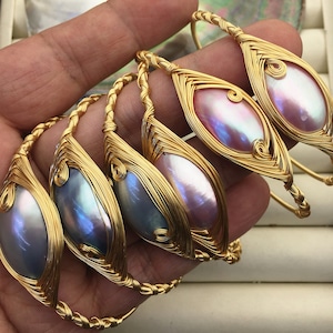 May include: Five gold wire wrapped bracelets with iridescent abalone shell inlays. The bracelets are stacked on top of each other.