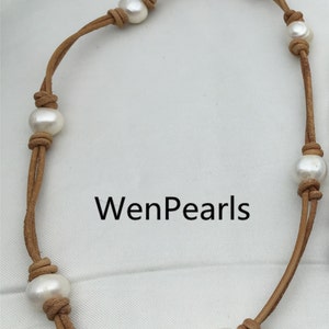 May include: A brown leather necklace with white pearls. The necklace is knotted with the pearls. The text "WenPearls" is visible in the image.
