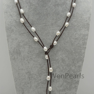 Peut inclure: Un collier en cordon de cuir marron avec des perles blanches. Le collier est réglable et peut être porté long ou court. Le collier est noué à l'avant.