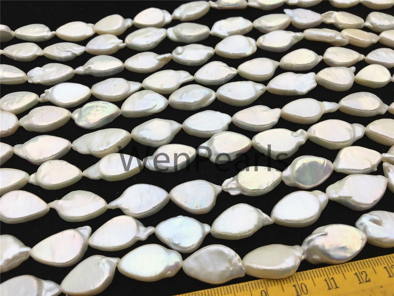May include: A strand of white freshwater pearls with an iridescent sheen. The pearls are shaped like teardrops and are arranged in a staggered pattern. The pearls are approximately 10 mm in length.