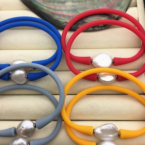 Peut inclure: Quatre bracelets en silicone avec un accent de perle. Les bracelets sont en rouge, bleu, gris et jaune.