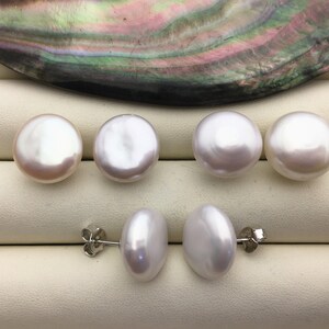 May include: A collection of white pearl earrings. The image shows six round pearls and two pairs of oval-shaped pearl earrings with silver posts. The pearls have a lustrous, iridescent sheen. The background features a pearlescent shell.