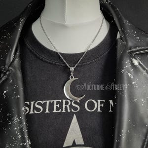 Silver crescent moon necklace on a mannequin with a gothic outfit and leather jacket.