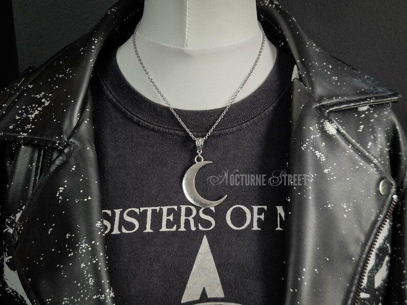 Silver crescent moon necklace on a mannequin with a gothic outfit and leather jacket.