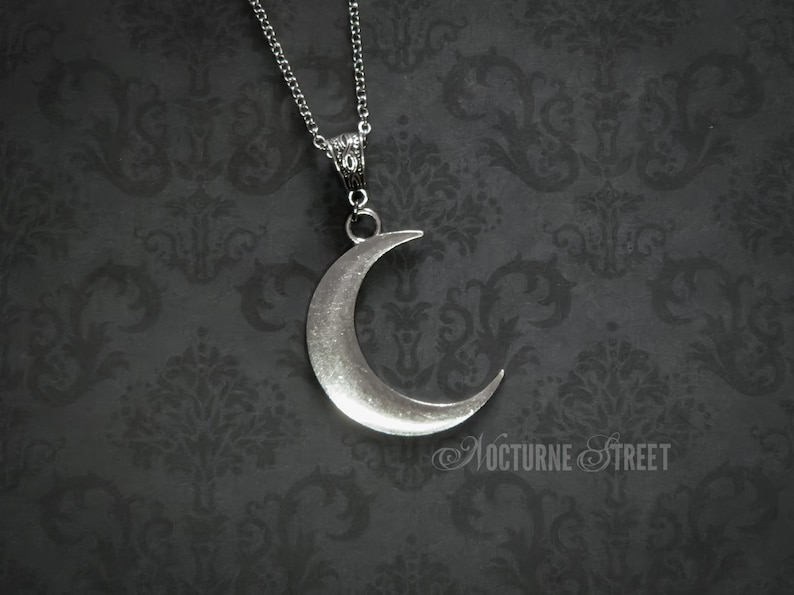 Silver crescent moon necklace on a dark gothic damask background.