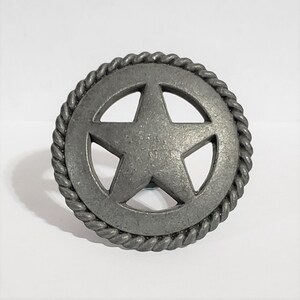 May include: A silver metal star with a rope border. The star is cut out and the rope border is raised.