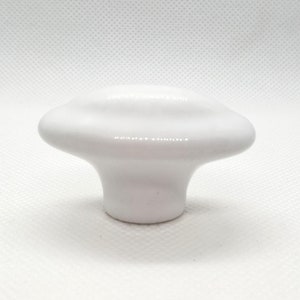 May include: White ceramic cabinet knob with a rounded, slightly oval shape. The knob has a smooth, glossy finish.