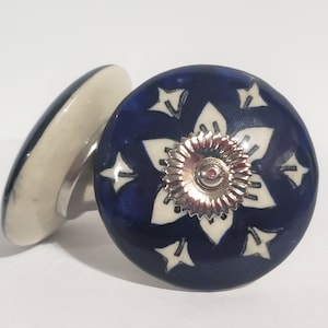 May include: Two ceramic knobs with a blue and white floral design. The knob on the right has a silver metal center.