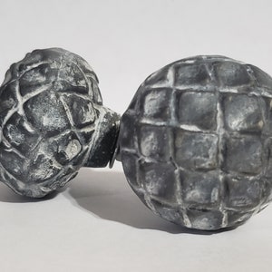 May include: Two black and white decorative knobs with a textured surface. The knobs are round and have a geometric pattern.
