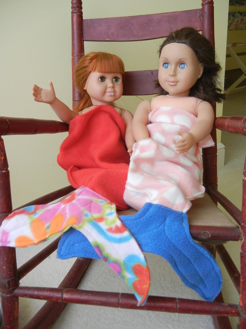 Image of dolls wearing doll mermaid tails:  red with flowered  tail  and  pink/white polka dot  with blue tail
