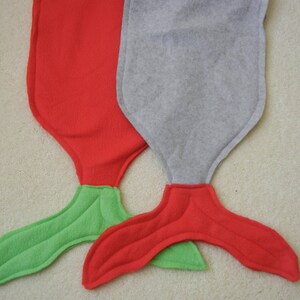 Image of doll mermaid tails: red with green tail ;  and  gray with red tail