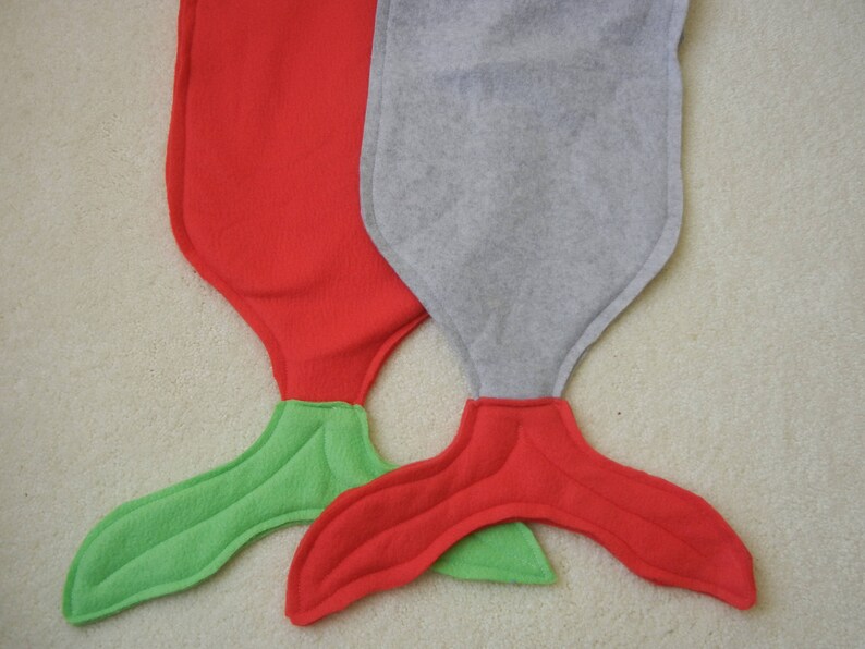 Image of doll mermaid tails: red with green tail ;  and  gray with red tail