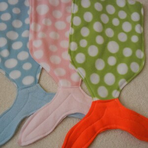 Image of doll mermaid tails: blue/white polka dot  with light blue tail;  pink/white polka dot  with pink tail;  and  green/white polka dot  with orange tail;