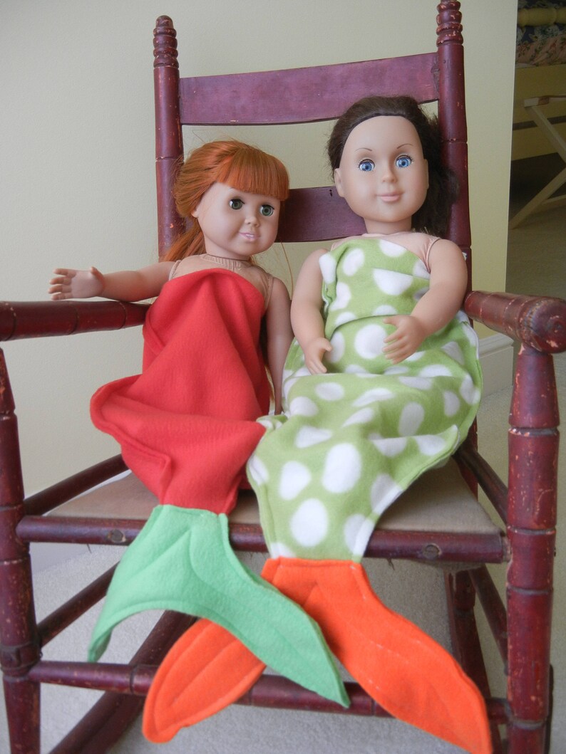 Image of dolls wearing  mermaid tails:  red  with green tail and  green/white polka dot  with orange  tail