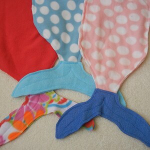 Image of doll mermaid tails:  red with flowered tail;  blue/white polka dot  with light blue tail;  and  pink/white polka dot  with blue tail