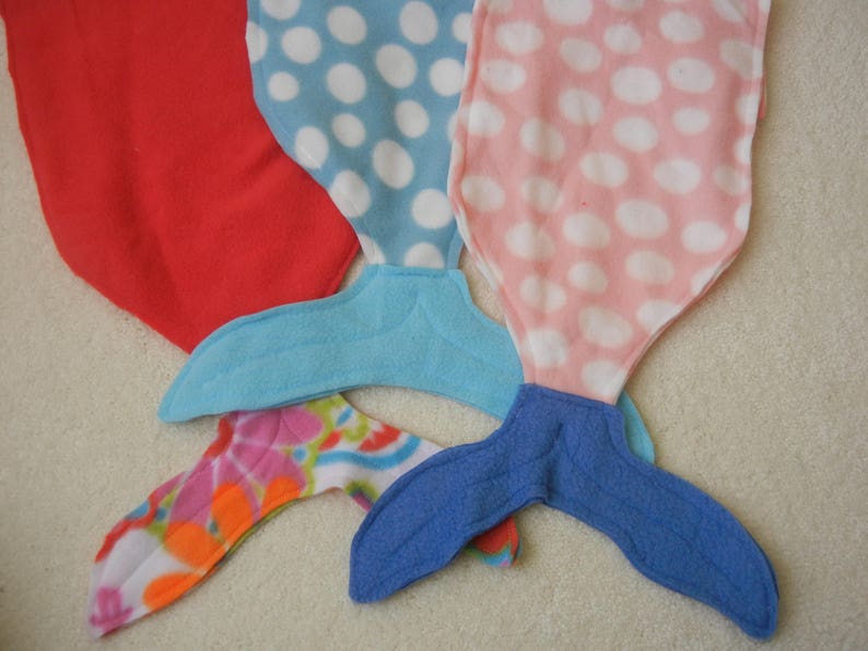 Image of doll mermaid tails:  red with flowered tail;  blue/white polka dot  with light blue tail;  and  pink/white polka dot  with blue tail