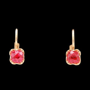 May include: A pair of gold-colored leverback earrings. Each earring features a four-leaf clover-shaped, faceted, bright red gemstone. The earrings are set against a black background.