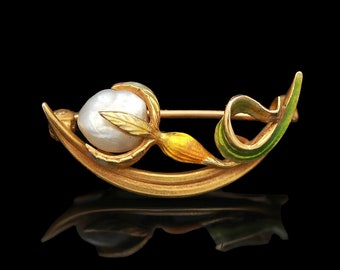 May include: A gold brooch with a pearl and enamel flower design. The flower is yellow, green, and white.