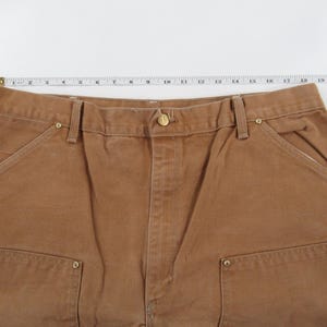 Puede incluir: Pantal&oacute;n de trabajo marr&oacute;n con m&uacute;ltiples bolsillos y cierre de bot&oacute;n.