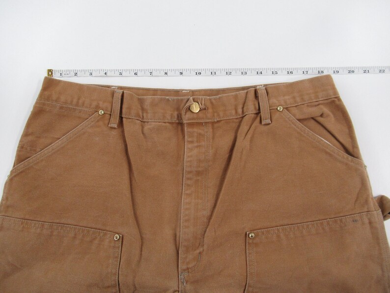 Puede incluir: Pantal&oacute;n de trabajo marr&oacute;n con m&uacute;ltiples bolsillos y cierre de bot&oacute;n.