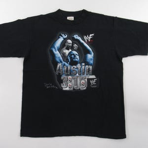 May include: Black t-shirt with a graphic of wrestler "Stone Cold" Steve Austin, with the text "Austin 3:16" and the WWF logo.