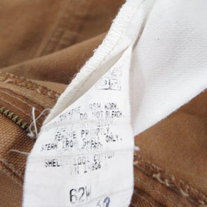 Puede incluir: Una etiqueta de cuidado blanca con texto negro unida a una tela marr&oacute;n. La etiqueta dice "NO BLANQUEAR.  ENJUAGAR INMEDIATAMENTE. PLANCHAR A VAPOR SOLO LA CAPA, CAPA: 100% ALGOD&Oacute;N TN14806 62W 38 x 32"