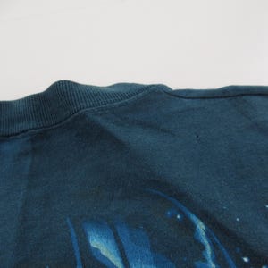 Puede incluir: Una camiseta azul oscuro con un dise&ntilde;o abstracto descolorido. El dise&ntilde;o parece ser una galaxia o nebulosa con estrellas y colores que se arremolinan.
