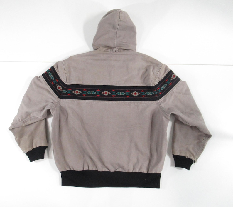 May include: A gray hooded jacket with a black and brown geometric pattern around the waist. The jacket has a black drawstring hood and a black elastic waistband.