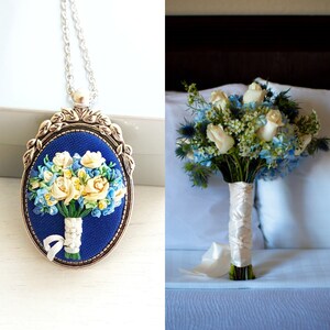May include: A blue and white embroidered bouquet of flowers in a silver frame pendant necklace and a matching bouquet of blue and white flowers.