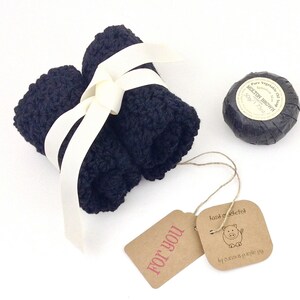 May include: A gift set with a black washcloth, a black bar of soap, and a brown gift tag that says "For You". The soap is wrapped in black paper and has a white label that says "Molton Brown" and "Pure Vegetable Oil Soap".