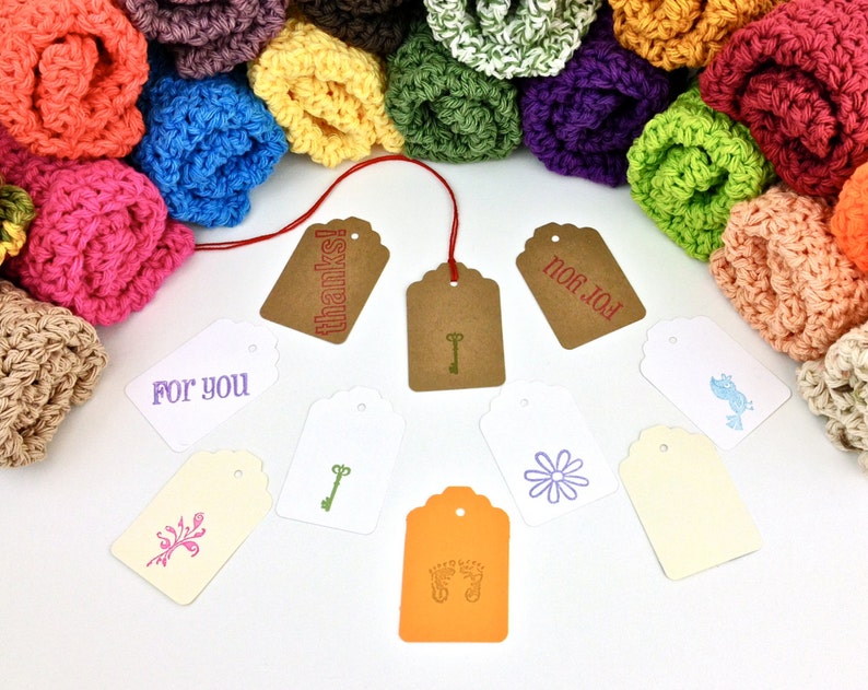 May include: A variety of colorful crocheted rolls with brown, white, and orange gift tags. The tags have different designs and text, including "For You", "Thanks!" and "For You".