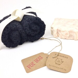 May include: A gift set with a black crocheted washcloth and a pink and white swirl soap bar. The gift set includes a brown tag with the text "For You" and a second tag with the text "handmade crocheted by curious purple pig".