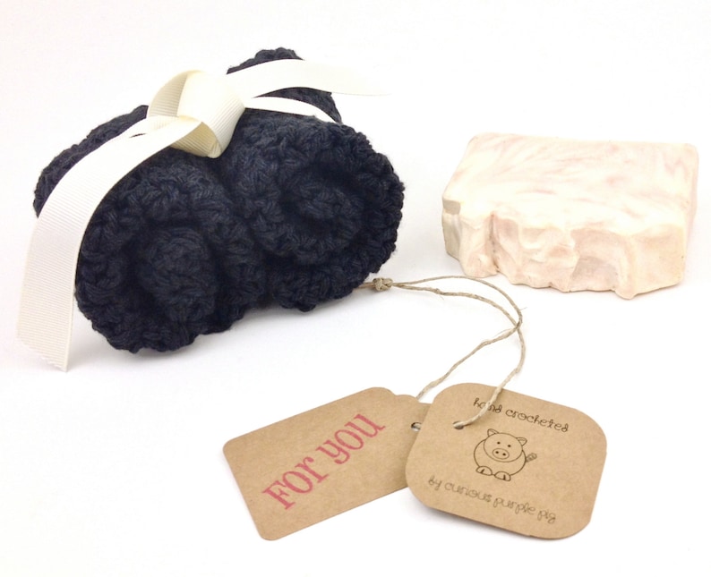 May include: A gift set with a black crocheted washcloth and a pink and white swirl soap bar. The gift set includes a brown tag with the text "For You" and a second tag with the text "handmade crocheted by curious purple pig".