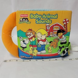 May include: A Fisher-Price Little People Baby Animal Sounds soft fabric book with a yellow cover featuring a red barn, farm animals, and children. A white measuring tape shows the book is approximately 10 inches wide. The text reads Baby Animal Sounds.