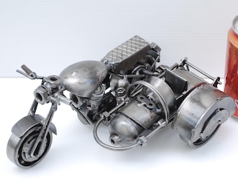 May include: A metal sculpture of a motorcycle with a sidecar. The sculpture is made from welded metal pieces. A Coca-Cola can is next to the motorcycle for size comparison.