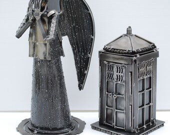 May include: A silver metal sculpture of a weeping angel from the Doctor Who television series, standing next to a silver metal TARDIS.
