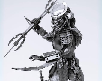 May include: A detailed, monochrome sculpture of a Predator figure, holding a trident and a bladed weapon. The figure is clad in intricate armour and features a distinctive helmet and mask. A chain hangs from the waist.