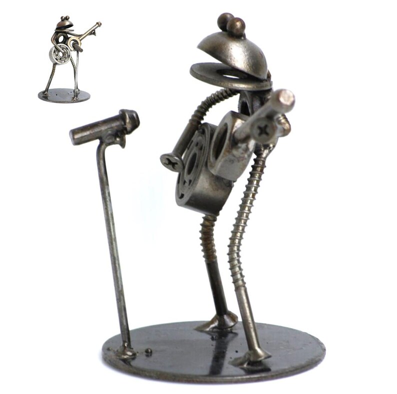 May include: A metal sculpture of a frog playing a guitar, with a microphone stand in front. The frog is made of nuts, bolts, and washers, with a round base. A smaller version of the sculpture is in the upper left corner.